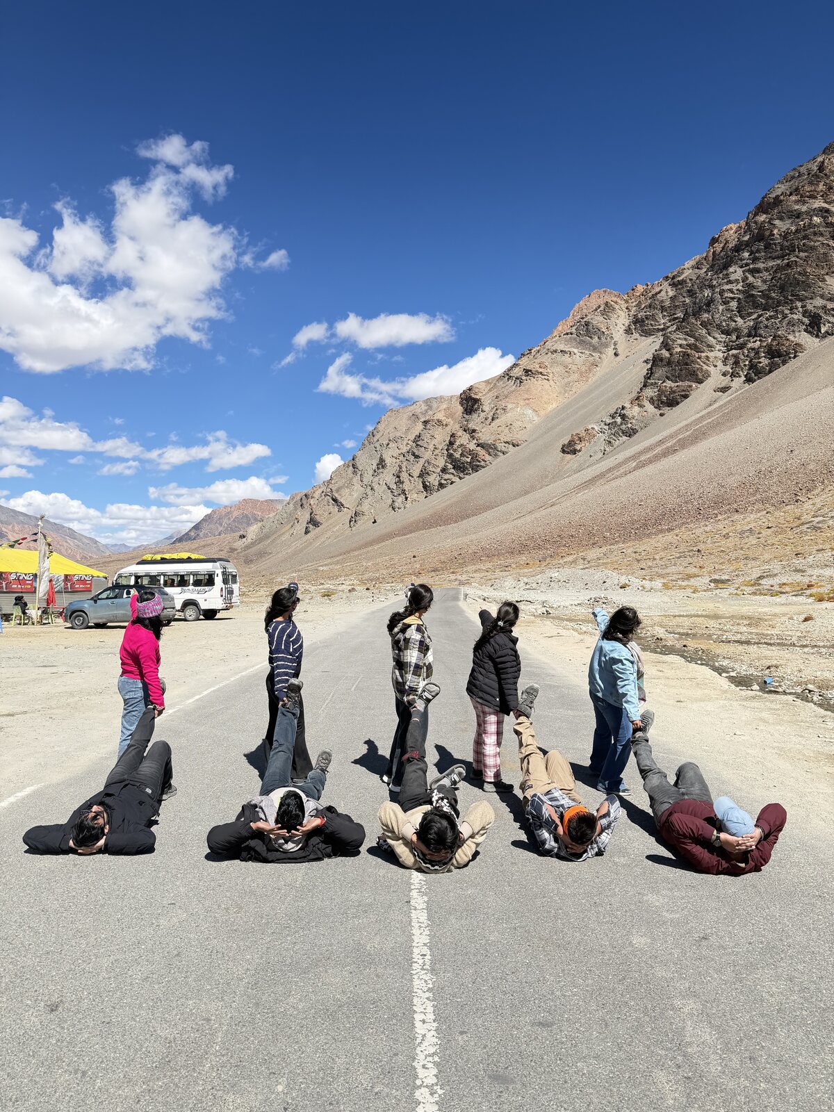 Travellers striking playful poses on an empty Himalayan road