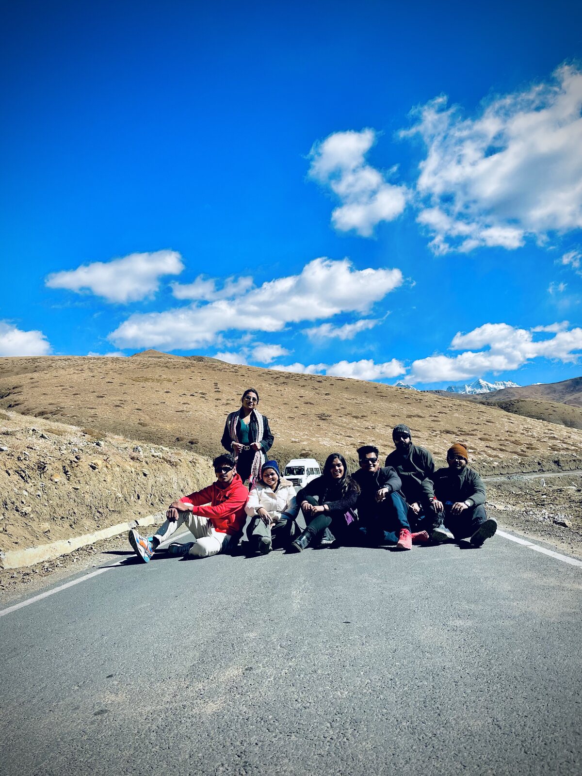 TRAVIA group sitting on a mountain road under a blue sky